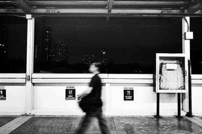 Blurred motion of woman walking on illuminated railroad station platform