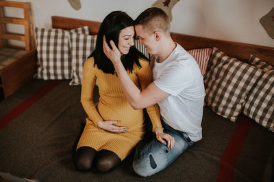 Midsection of couple sitting at home