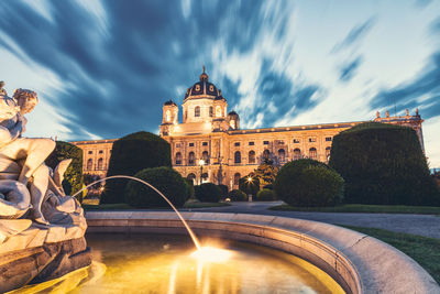 Illuminated fountain building against sky in city