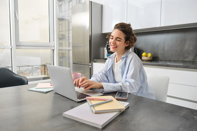 Portrait of young woman using laptop at table