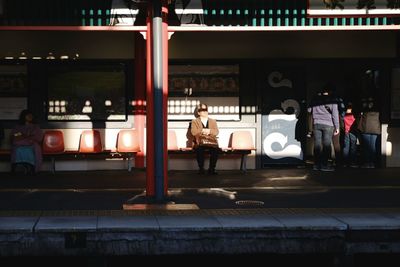 Woman sitting on railroad station platform at night