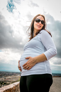 Beautiful young woman standing against sky