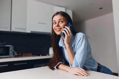 Young woman using mobile phone while sitting at home