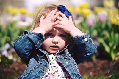 Close-up portrait of girl with head in hands on sunny day