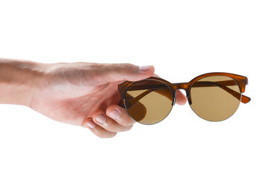 Close-up of hand holding sunglasses against white background