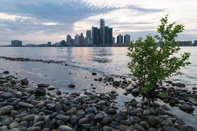 View of city by sea against cloudy sky