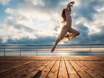 Young woman jumping on sea against sky