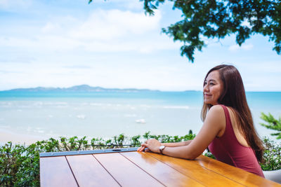 Portrait of smiling young woman looking away against lake