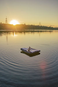 Young woman lies on a mattress on the lake during sunset