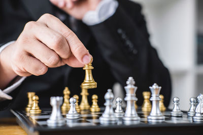 Midsection of businessman playing chess at desk