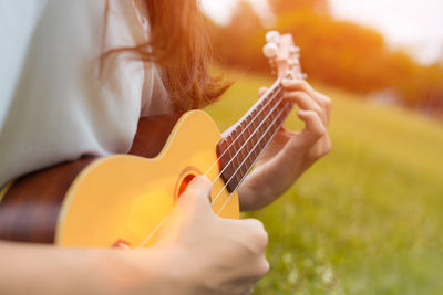 Midsection of woman playing ukulele on grass