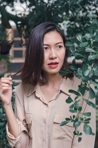 Portrait of beautiful woman standing against plants