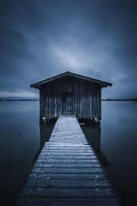 Pier over sea against cloudy sky at dusk