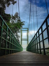 Footbridge amidst trees against sky