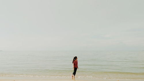 Full length of woman standing on beach against sky