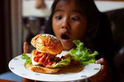 Girl looking at burger in plate
