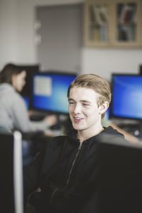 Smiling high school teenage student using computer in classroom