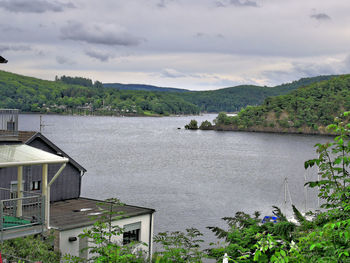 Scenic view of river by buildings against sky