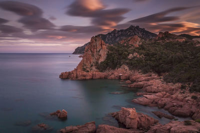 Scenic view of rock formations by sea against sky during sunset