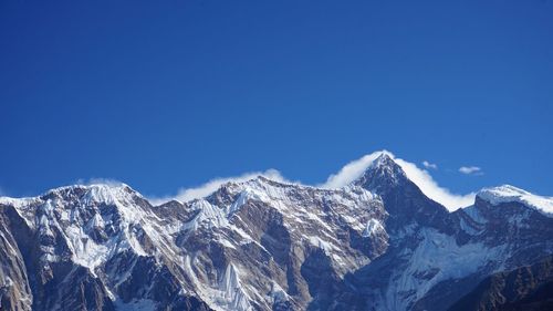 Scenic view of snowcapped mountains against clear blue sky