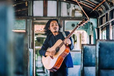 Young guitarist playing guitar in bus