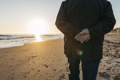 Senior man strolling at the beach, rear view