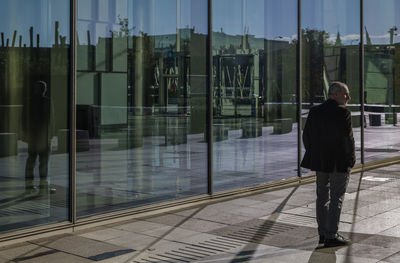 Portrait of adult man in suit against glass wall, city business centre