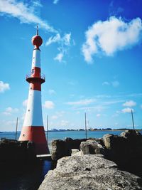 Lighthouse by sea against sky