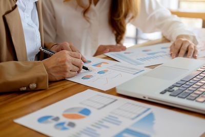 Midsection of businesswomen discussing over documents in office