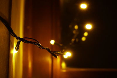 Close-up of illuminated lighting equipment hanging by wall