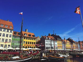 Sailboats moored on canal by buildings in city against sky