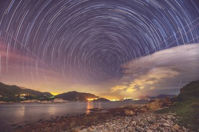 Scenic view of river against star trails at dusk