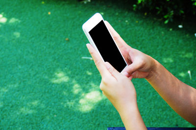 Midsection of person using mobile phone in grass