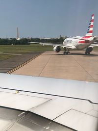 Airplane on airport runway against sky