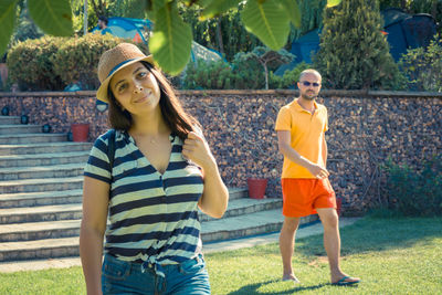 Portrait of smiling young woman standing against plants