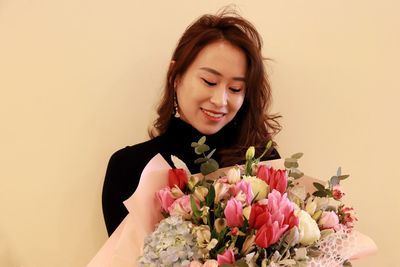 Beautiful woman with pink flower against wall