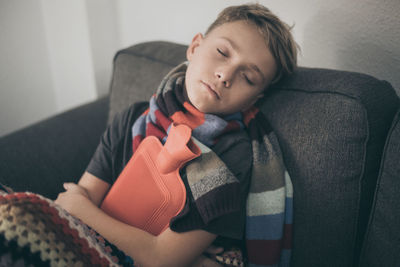 Boy with hot bag sleeping on sofa at home