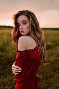 Portrait of beautiful woman standing on land against sky during sunset