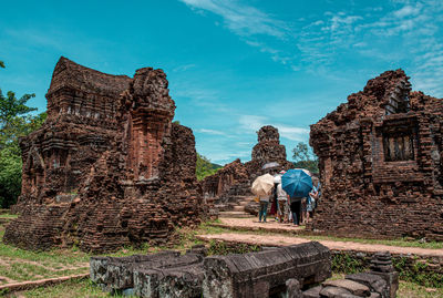 Tourists at old temple against sky