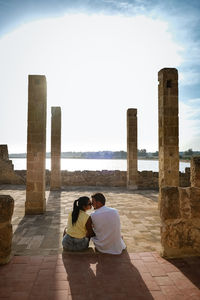 Rear view of couple sitting against sky