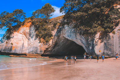 People on rocks at beach against sky