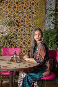 Portrait of smiling young woman sitting on table