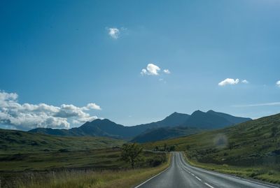 Country road along landscape against sky