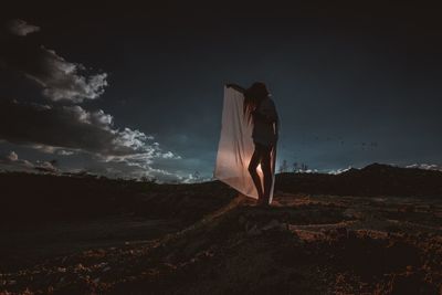 Rear view of woman standing on landscape against sky