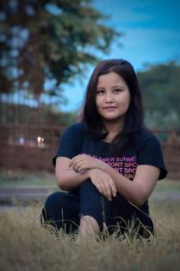 Portrait of young woman sitting on land