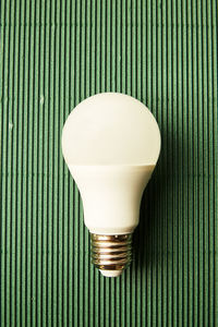 Close-up of light bulb on green textured table