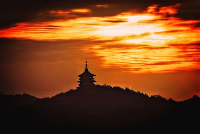 Silhouette of building against cloudy sky during sunset