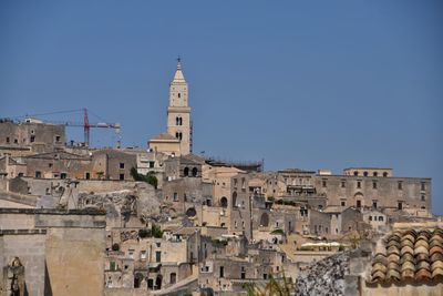 Buildings in city against clear blue sky