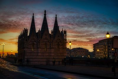 Illuminated building against sky at sunset