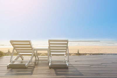 Deck chairs on beach against clear sky